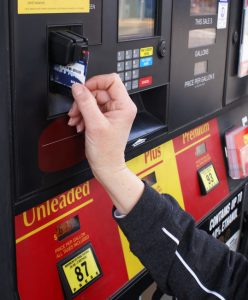 Woman's hand inserting a credit card into an automated gas pump