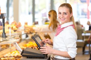 Shopkeeper or saleswoman at bakery working at cash register